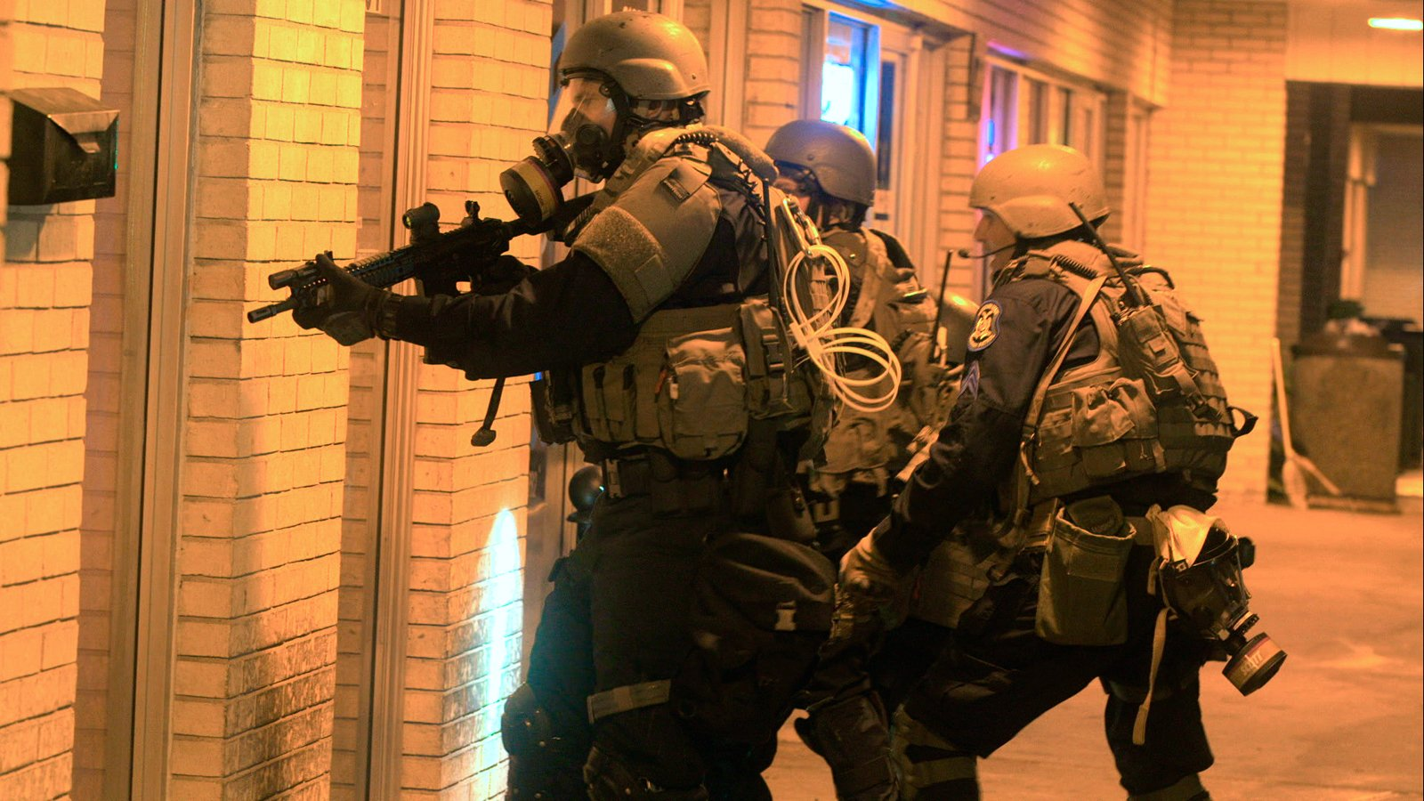 Militarized Police with guns drawn in front of doors