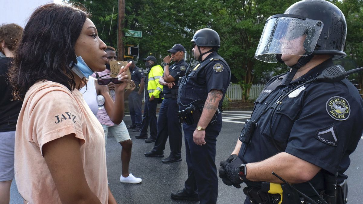Woman in front of officer in riot gear
