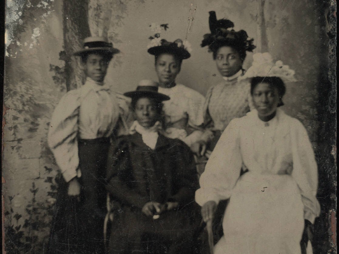 Five women all with hats with a forest backdrop
