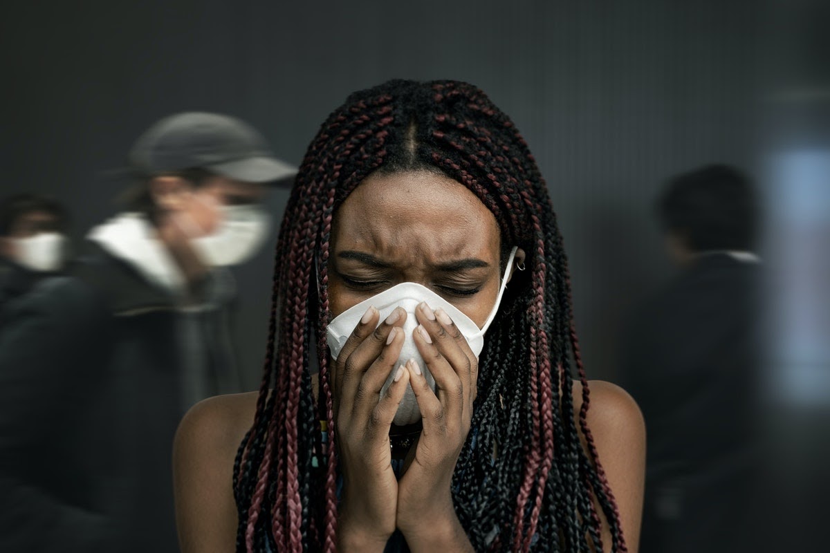Woman with hands covering her face mask