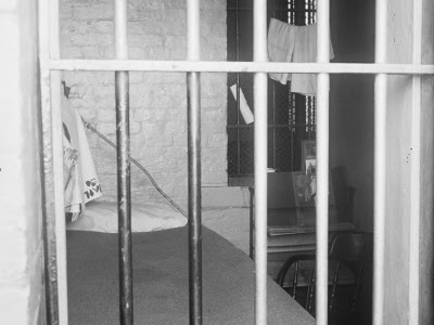 black and white photo of empty jail cell 