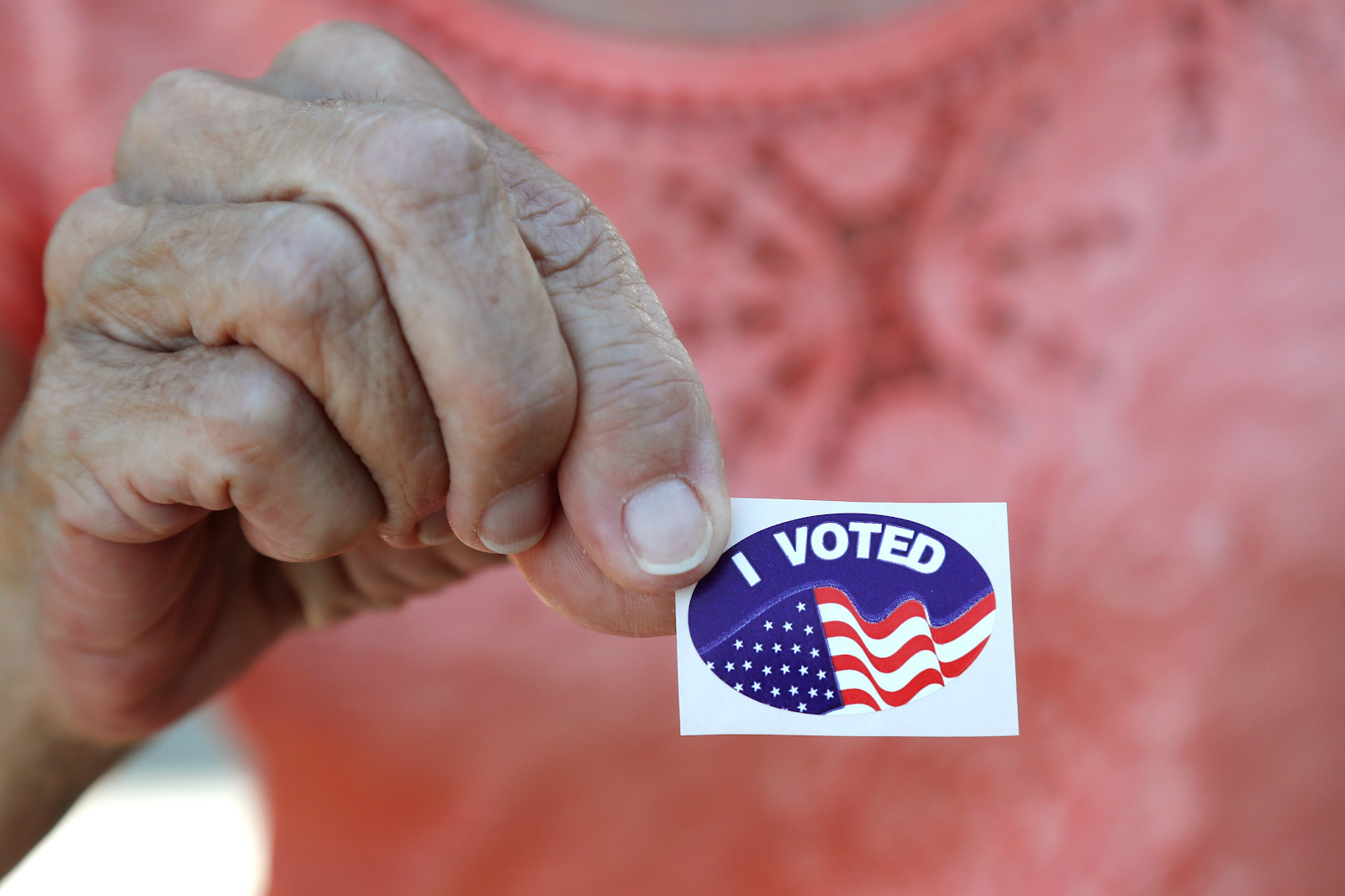A hand holding an "I Voted" sticker