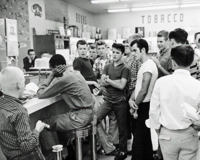 white people surrounding black man doing a sit in protest