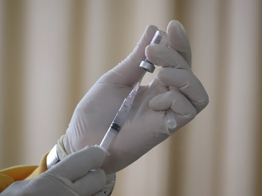 needle being held drawing liquid from a clear vial 