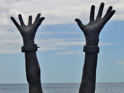 hands with shackles around the wrists reaching up