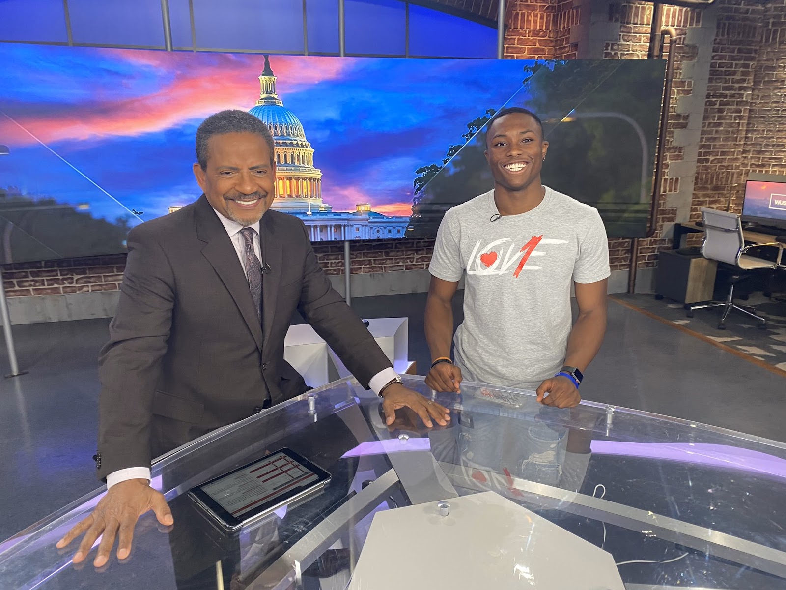 Student smiling with anchor at news desk