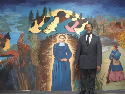 man standing next to a portait of harriet tubman 