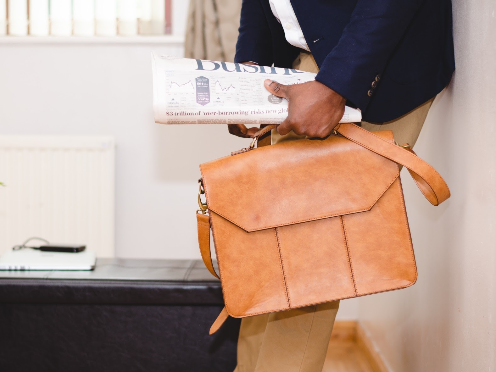 Person holding briefcase and newspaper