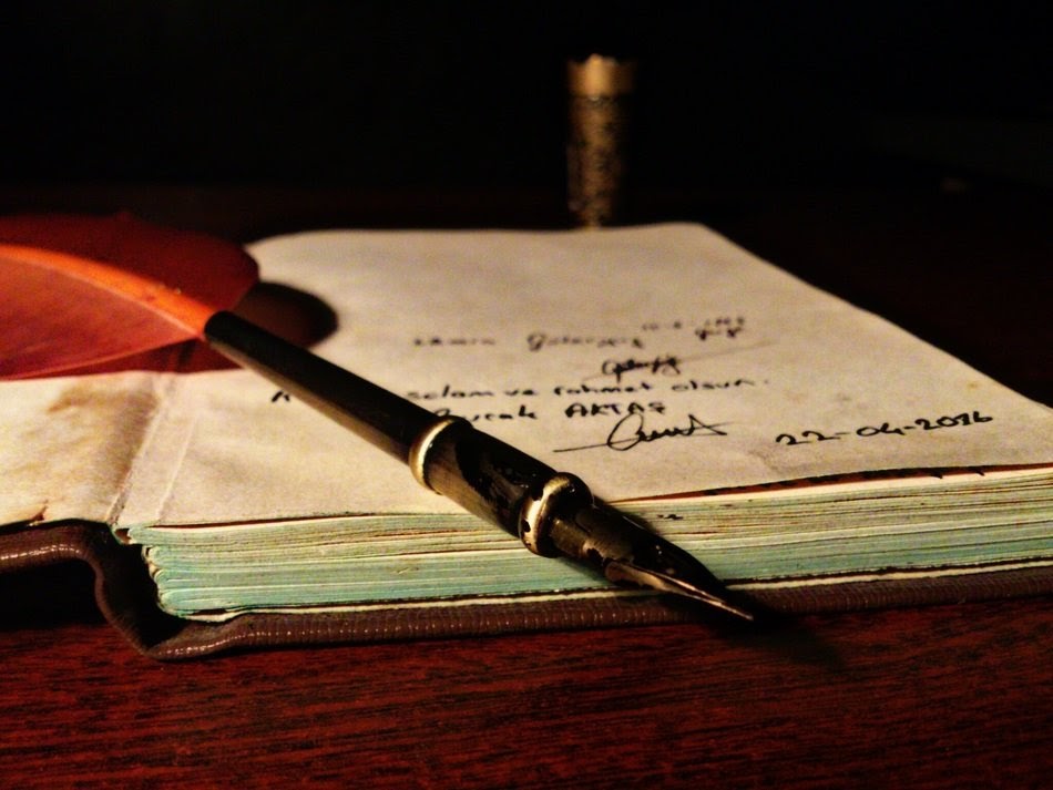 Ink pen with feather on an open book