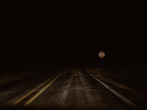 dark road with a stop sign at the end 