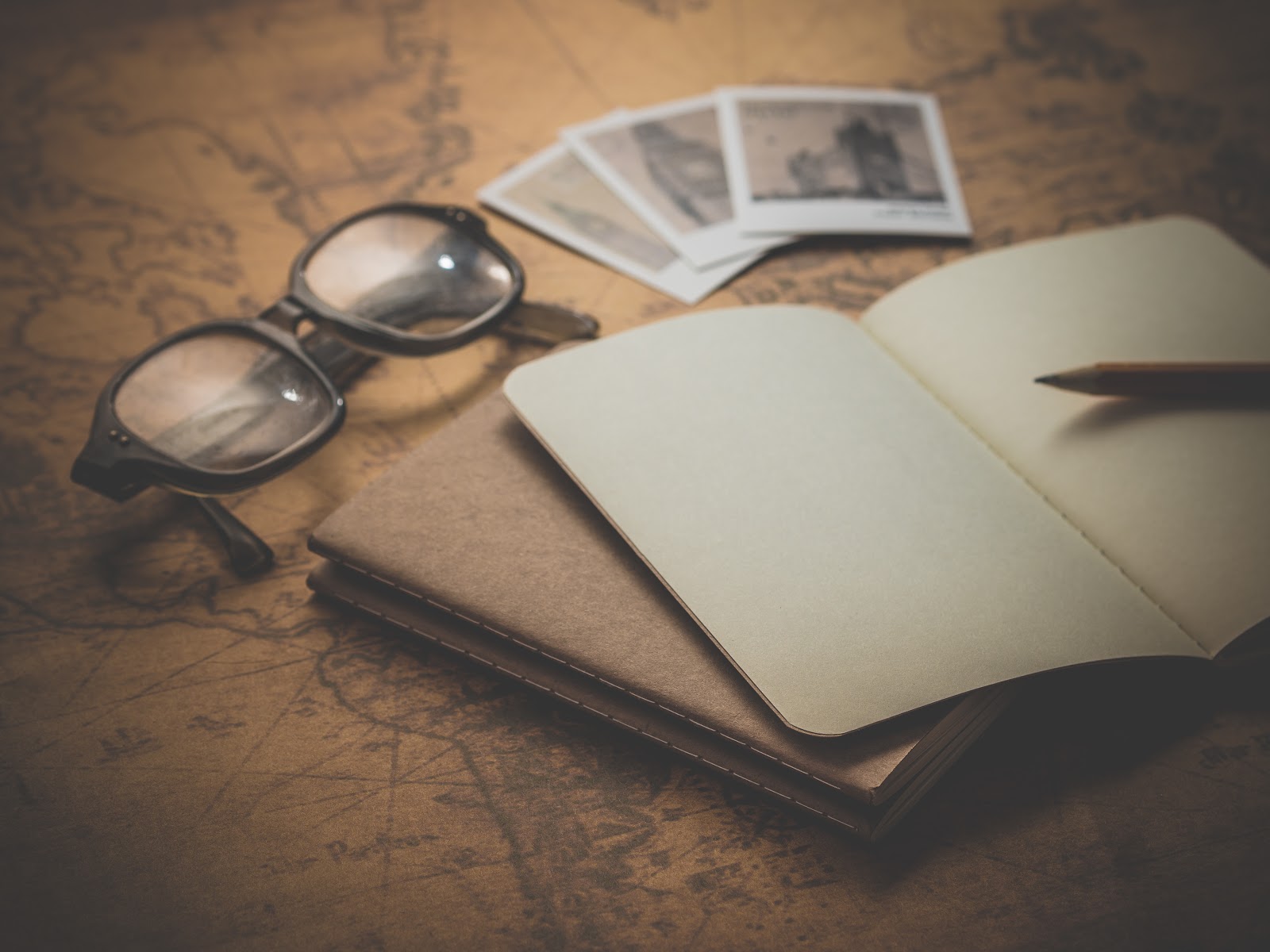 A pair of glasses, photos and journal on a world map