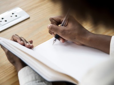 black woman writing in blank journal