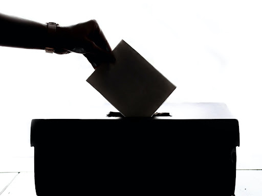 person putting a paper into a box with a slit 