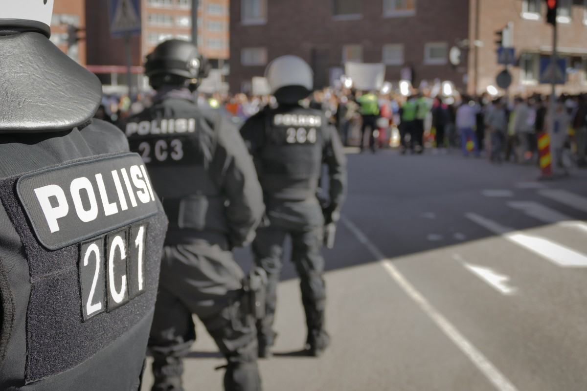 Police in riot gear facing protestors down the street