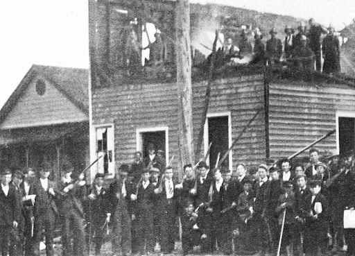 Group of white wWilmington residents in front of burnt down home