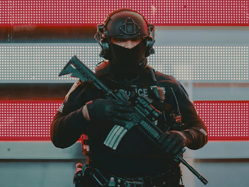 man in police riot gear holding a rifle