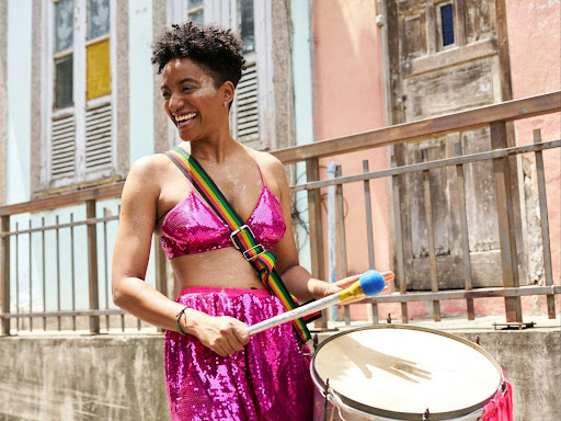 a woman in a pink outfit holding a drum 