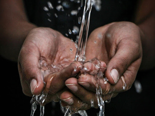 hands cupped together under running water