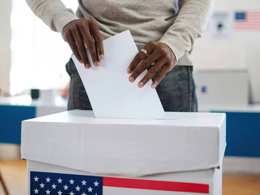 person putting ballot in ballot box