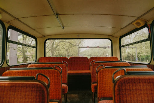 an empty bus with orange seats and. trees in the background