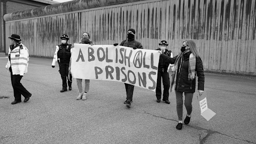 people holding banner that says abolish all prisons