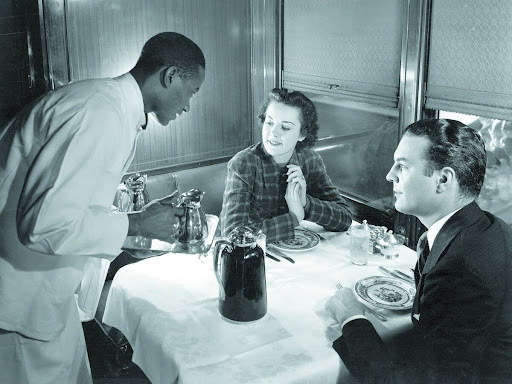 black waiter serving white couple
