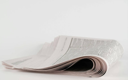 a stack of newspapers sitting on top of a white table