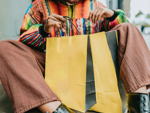 a woman sitting on the ground holding a yellow shopping bag