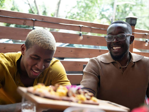 a couple of men sitting at a table with a plate of food 