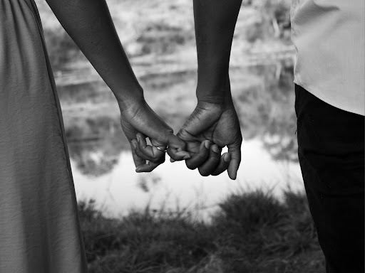 a black and white photo of two people holding hands