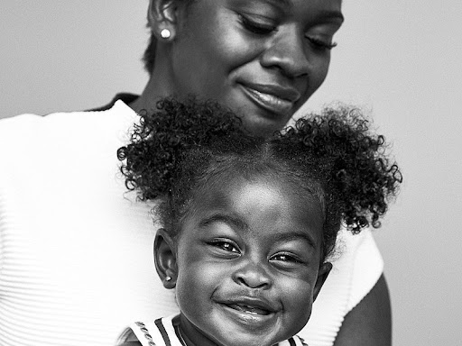 black and white image of toddler girl being held by mom 