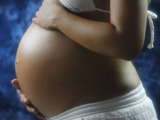 black woman holding her pregnant stomach