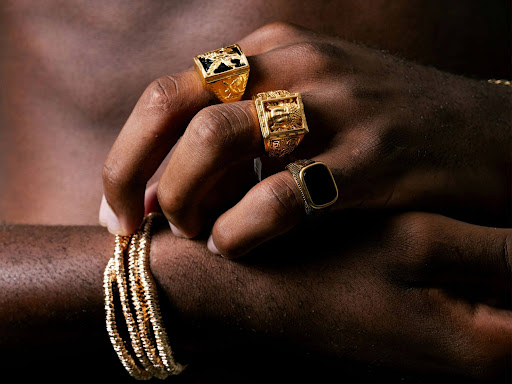 persons hands adorned with gold rings and bracelets