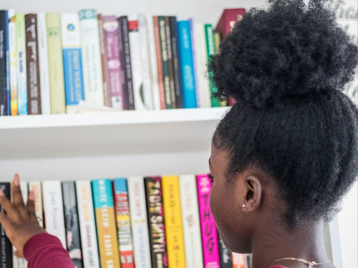 young black girl looking at books on shelves
