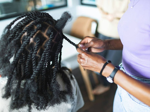 young black woman working at home making afro braids
