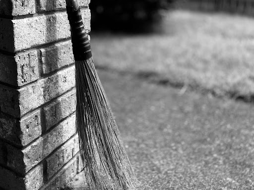 brick wall with a broom leaning up against it 