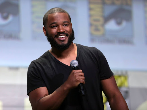 ryan coogler smiling while holding a microphone