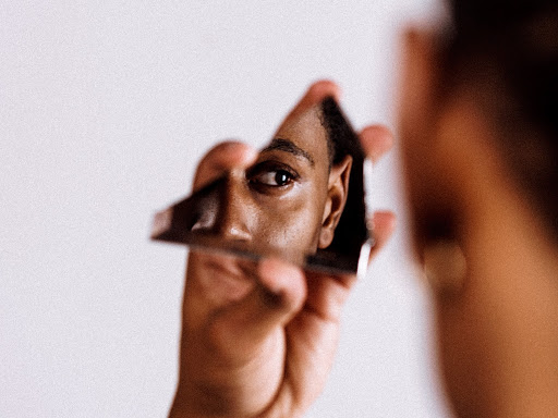 person looking at themselves through a mirror shard they are holding