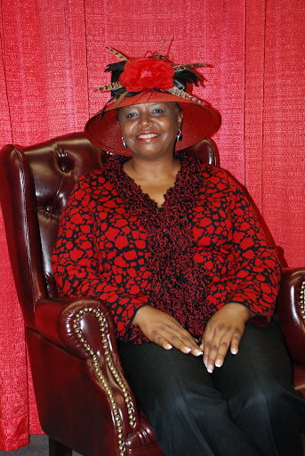 black woman sitting in a chair with a red hat on