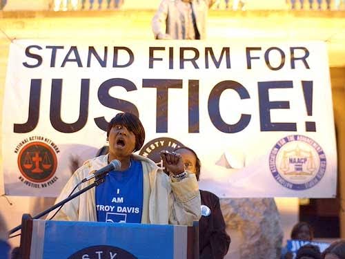 person standing behind a banner that says stand firm for justice