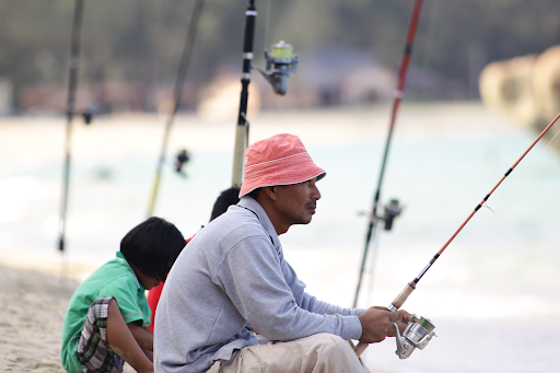 man sitting on the edge fishing on river