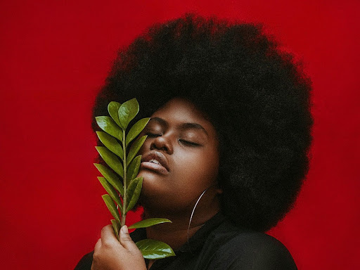 black woman in black crew shirt holding green plant