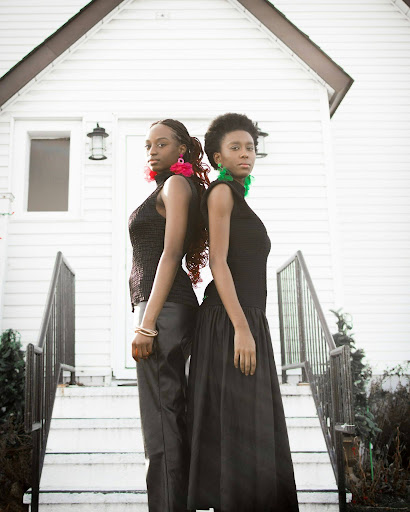 two women standing front of a white house