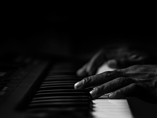 grayscale photo of person playing piano
