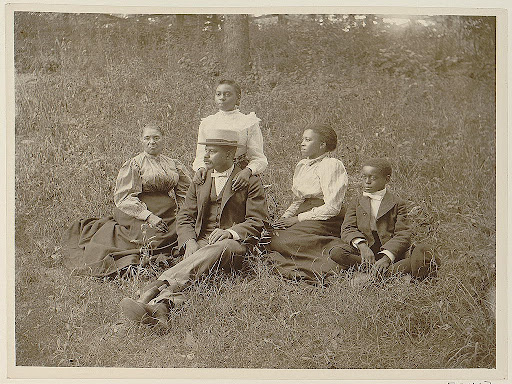 black family sitting down in grass