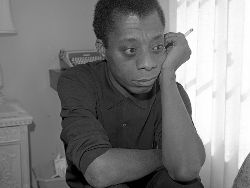 james baldwin sitting down holding a cigarette