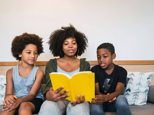 portrait of black mother reading a book to her children 