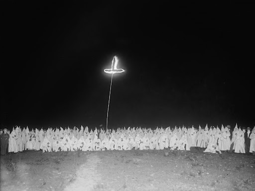 ku klux klan members standing around a burning cross