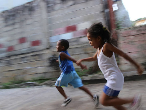 boy and girl running beside a gray wall