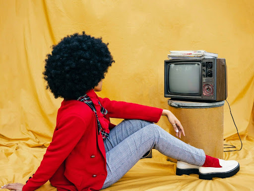 woman sititng on the ground next to a tv